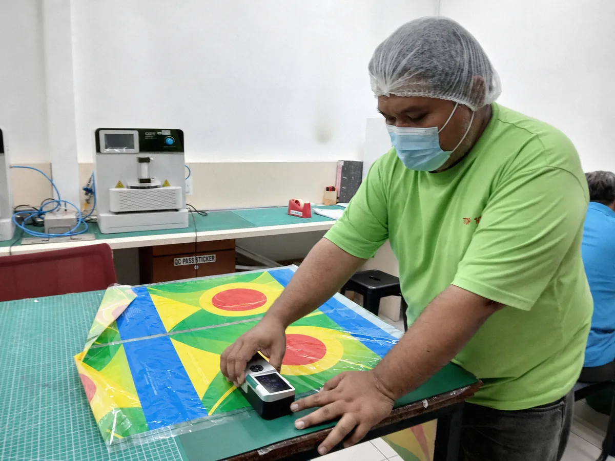 QA technician measuring printed film with a spectrophotometer